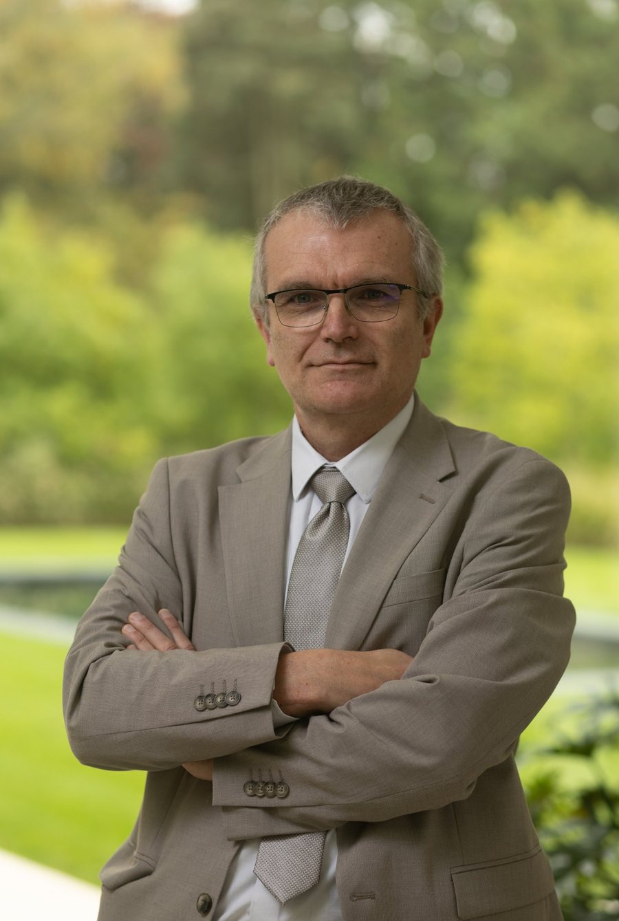 Portrait du second associé, bras croisés, devant un jardin