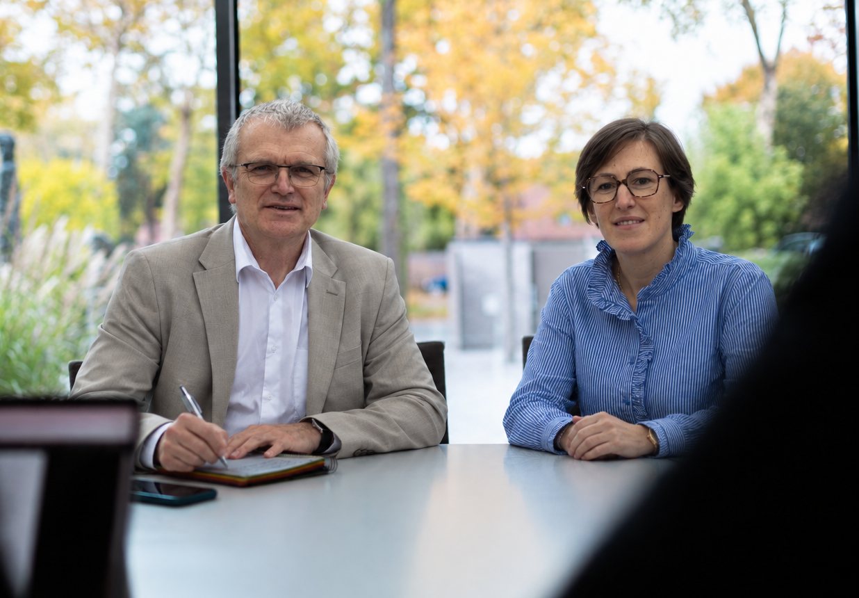 Les deux associés à la table d'un premier échange, un carnet à la main